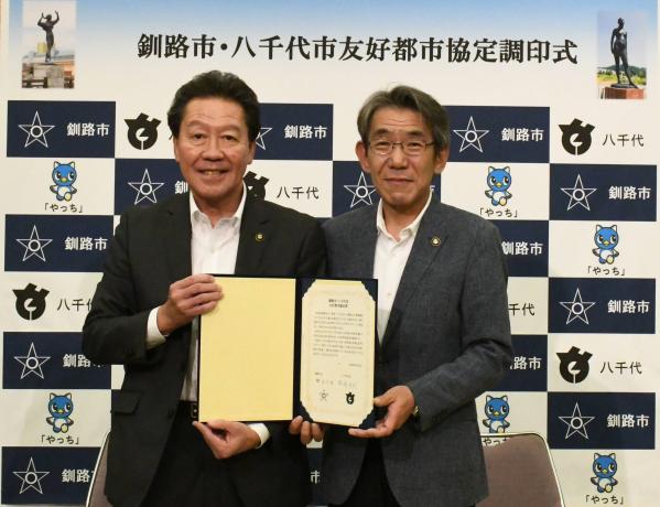 協定書を手にする服部八千代市長と蝦名釧路市長の画像