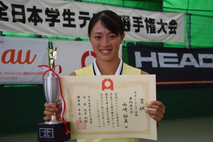 優勝カップと賞状を掲げる山崎選手